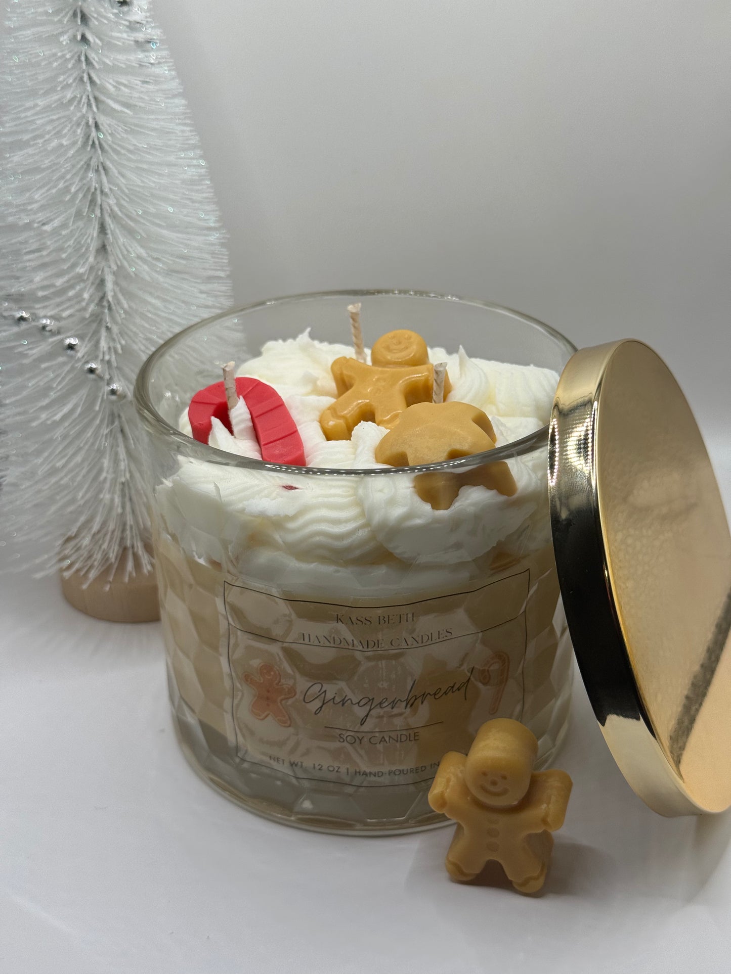 Gingerbread-themed candle with gingerbread men decorations on a white surface.