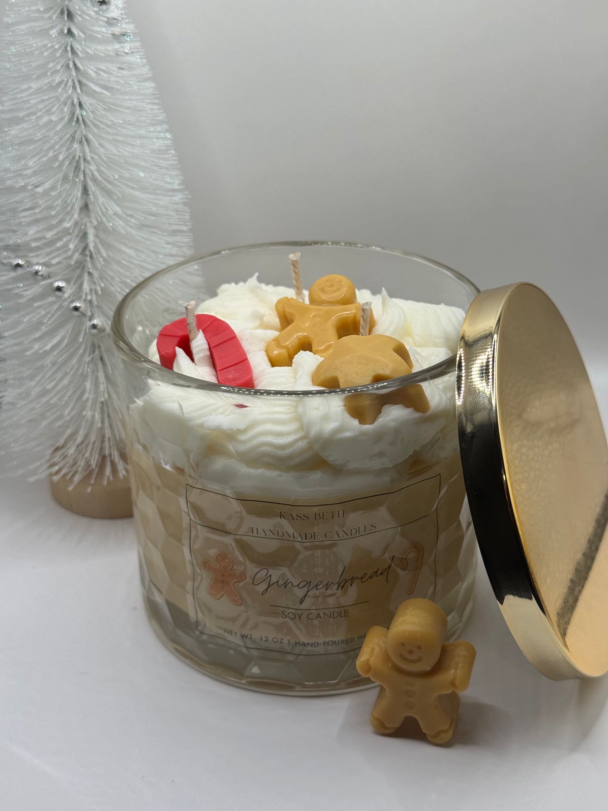 Gingerbread-themed candle with gingerbread men decorations on a white surface.